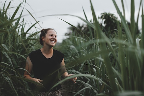 Woman laughing as she walks through tall grass. 